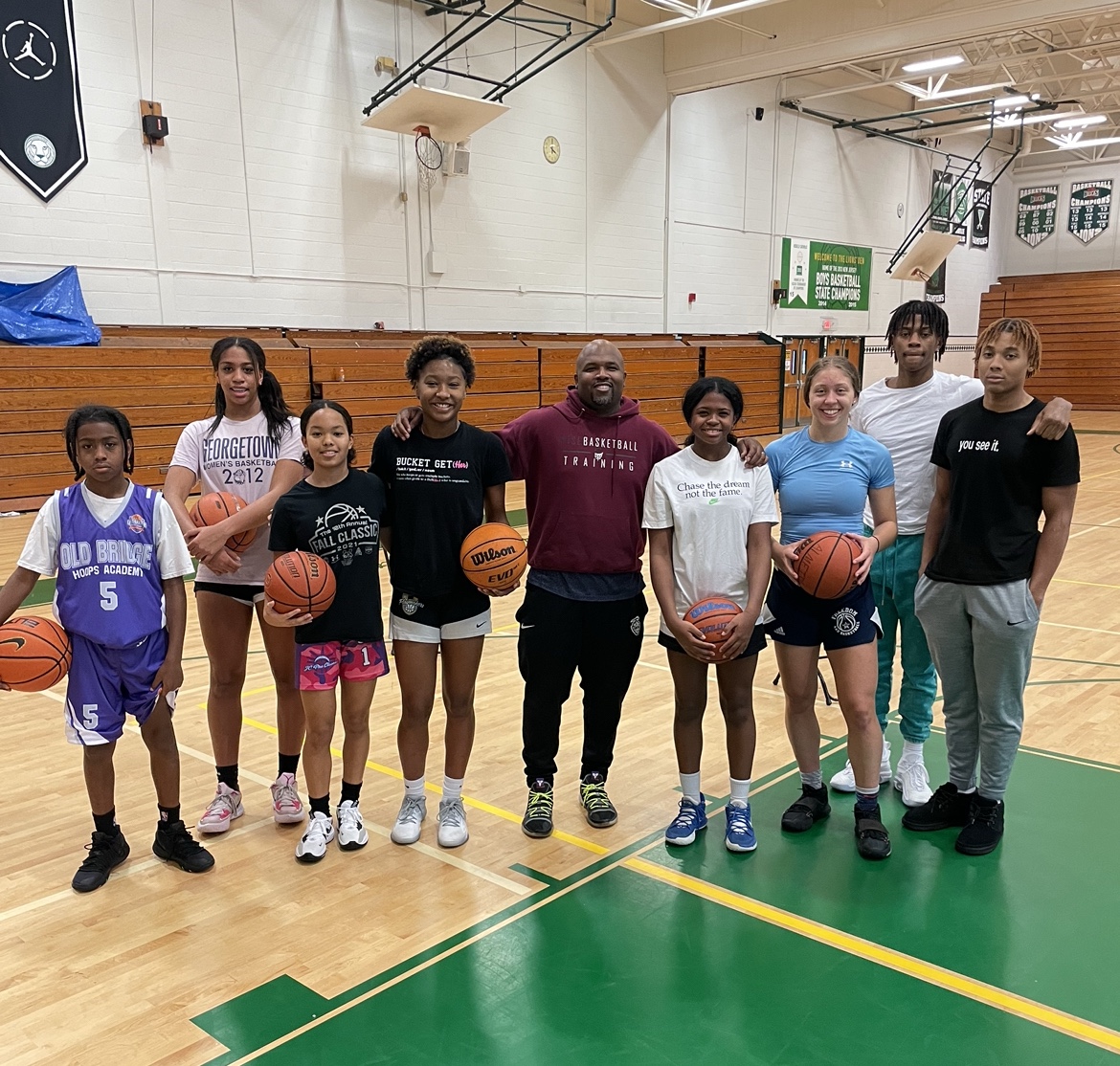 Coach Jamar Wise in a burgundy hoodie with a group of young athletes
